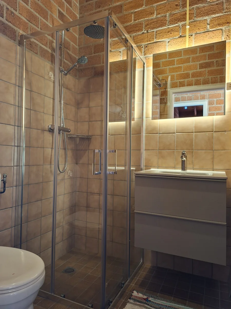 De badkamer met douche, wastafel en spiegel