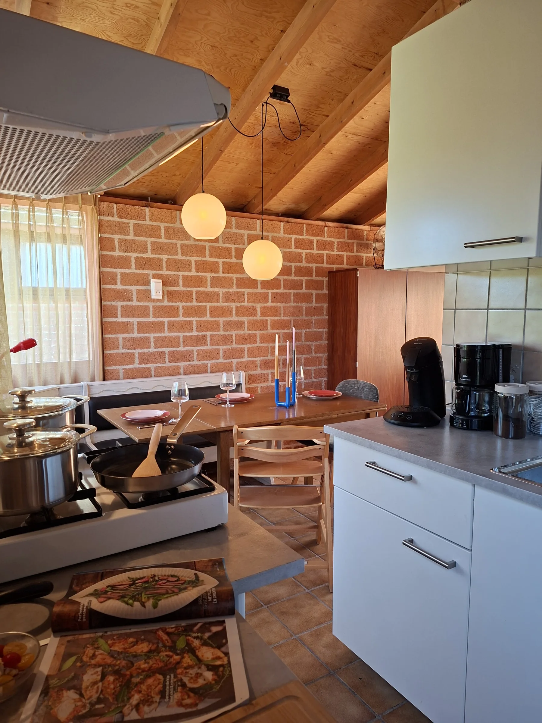 De keuken met houten werkblad, open planken en de eethoek op de achtergrond